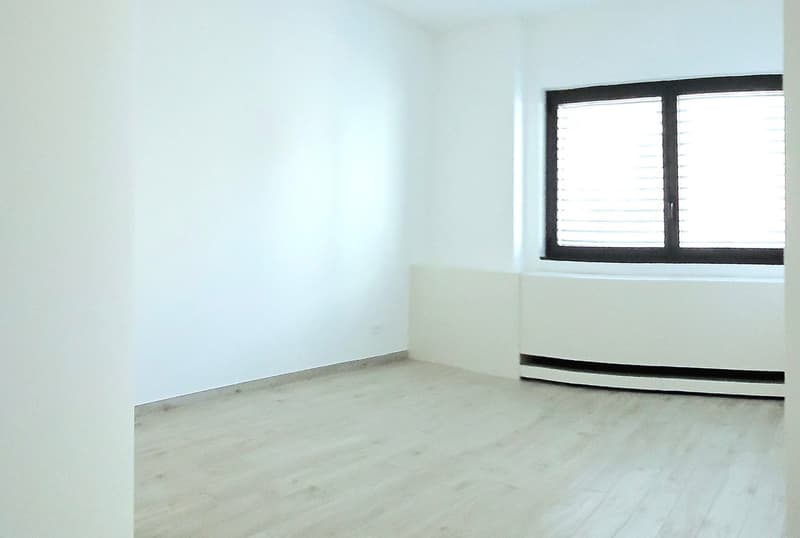 empty room, white walls, wooden floor, window, heating unit