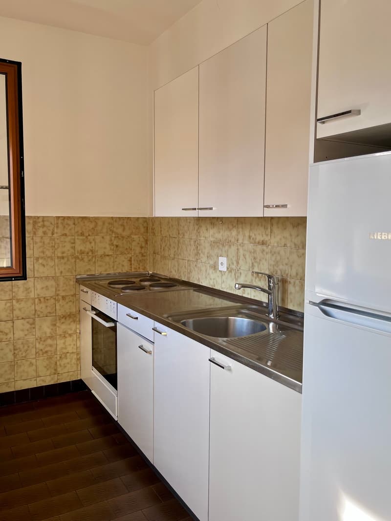 modern kitchen with white cabinets, stainless steel countertop, gas stove, oven, sink, refrigerator