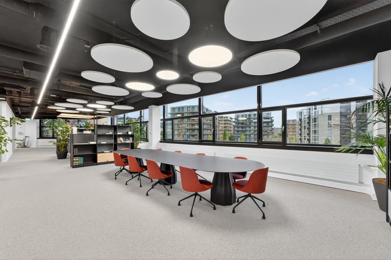 large meeting room with long table, large windows, modern lighting, plants, carpet floor