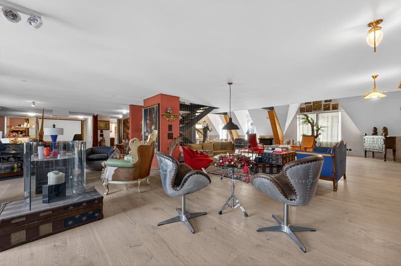 spacious room, wooden floor, various chairs and tables, decorative items, lamps, staircase, paintings on wall