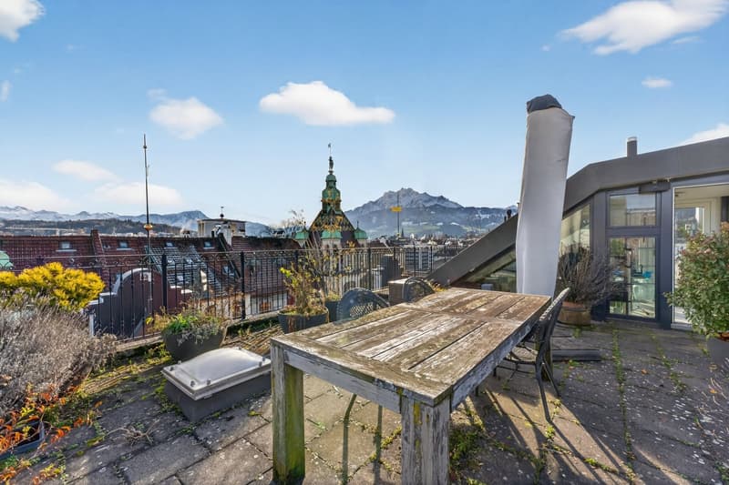 wooden table, chairs, plants, metal railing, mountains in the distance