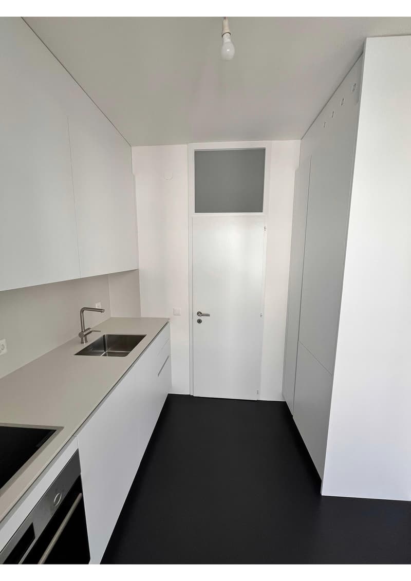 modern kitchen with white cabinets, black floor, stainless steel sink, faucet, built-in oven, dishwasher, washing machine