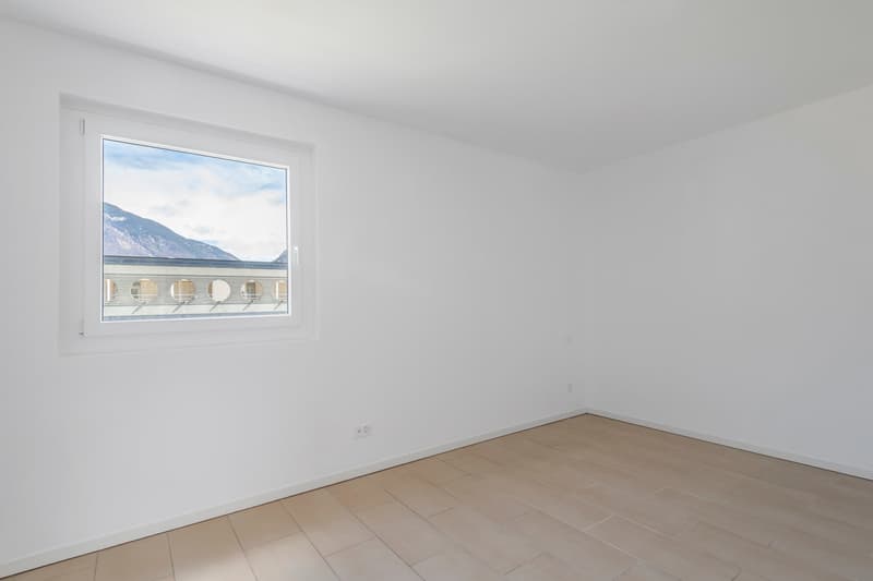 Empty room, white walls, wooden floor, large window with scenic mountain view