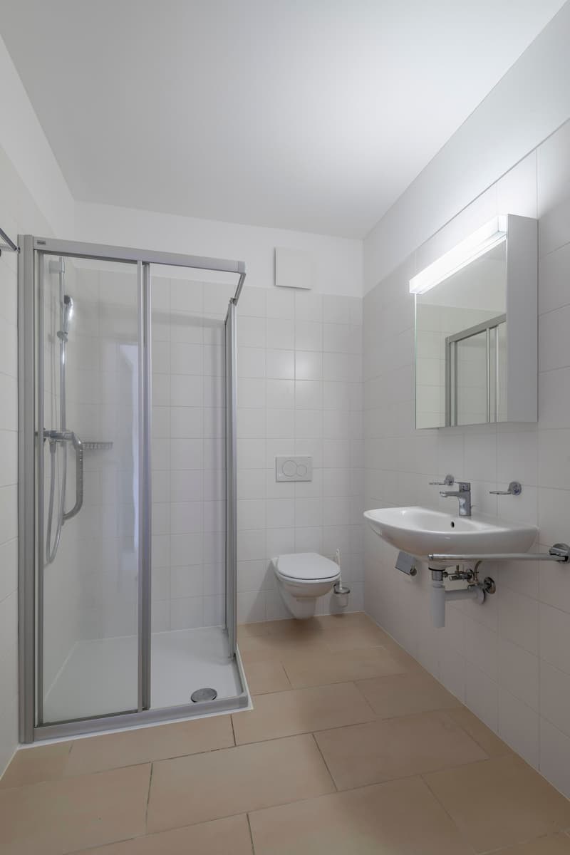modern bathroom with shower, toilet, sink, mirror, and tiled floor