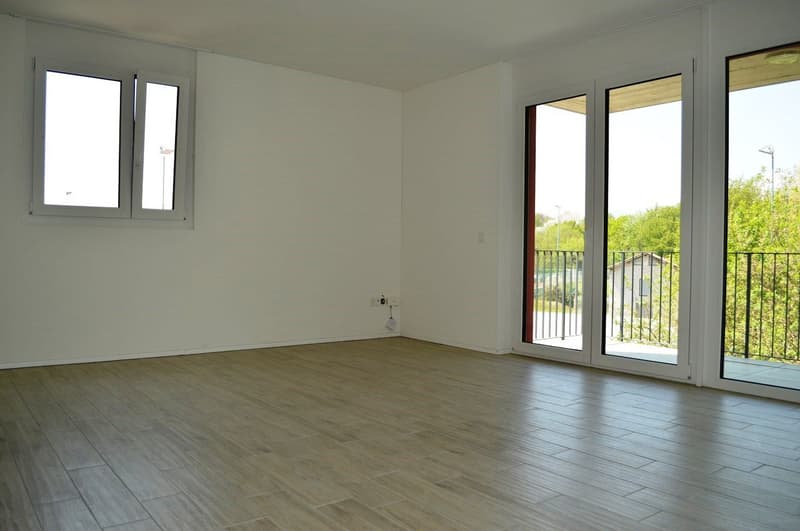 Tiled floor, white walls, sliding glass doors to balcony, power outlets, two windows