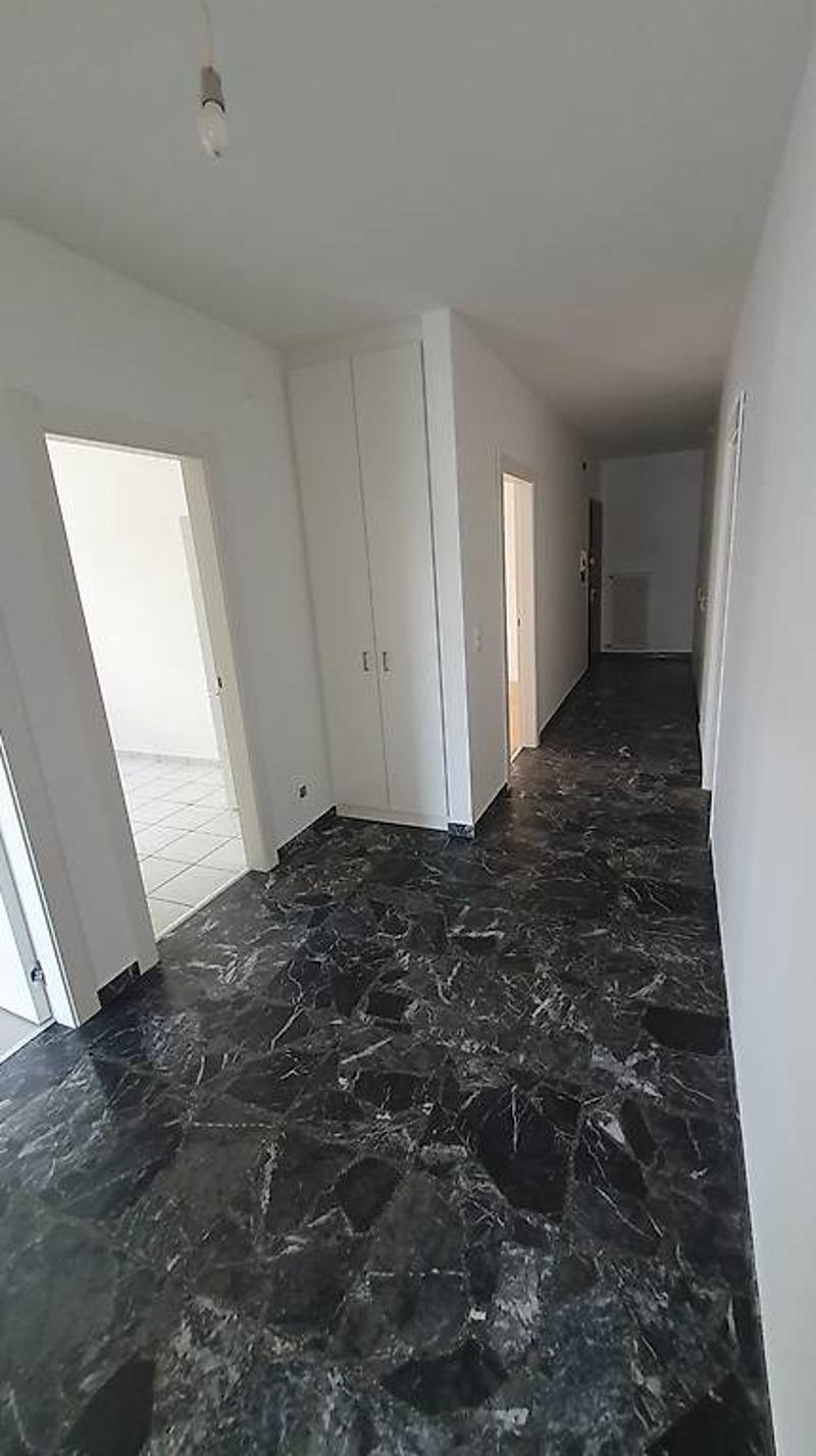 The image shows a hallway with white walls and a black marble or granite floor. There are several doors leading to other rooms along the hallway.