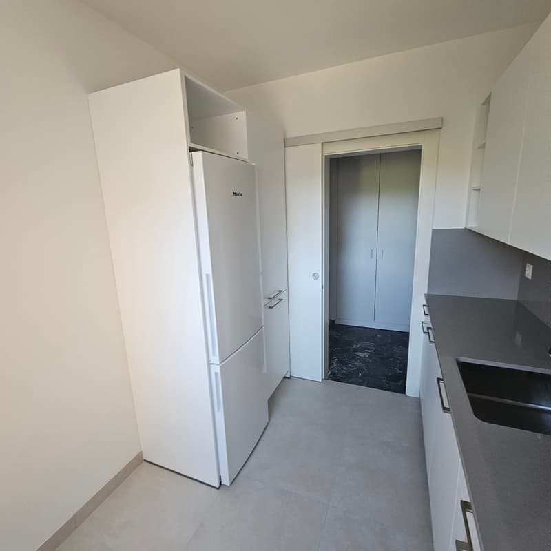 White refrigerator, black countertops, sliding door, gray tile flooring