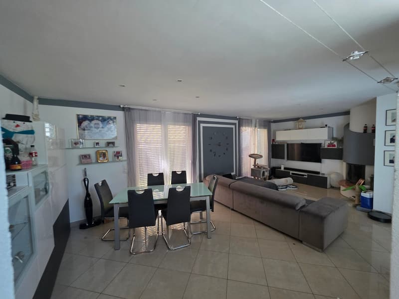 Dining room with a table and chairs, a couch, a television, and a fireplace.