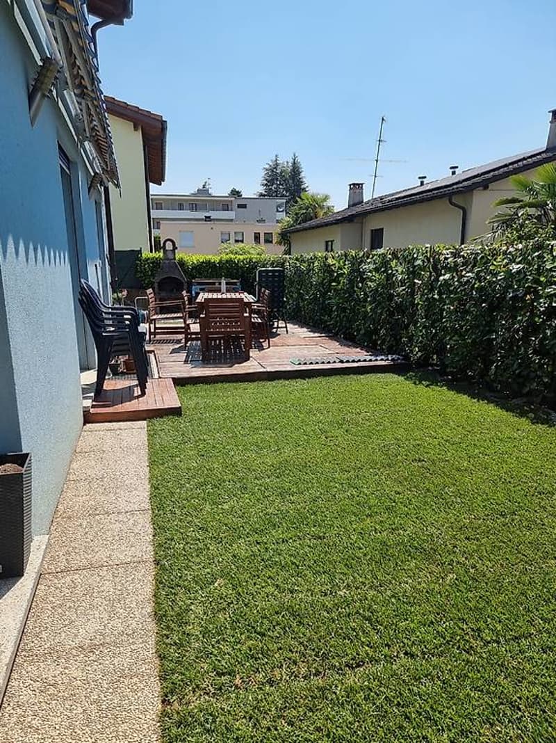 well-maintained garden with a wooden deck, outdoor seating, and a barbecue area