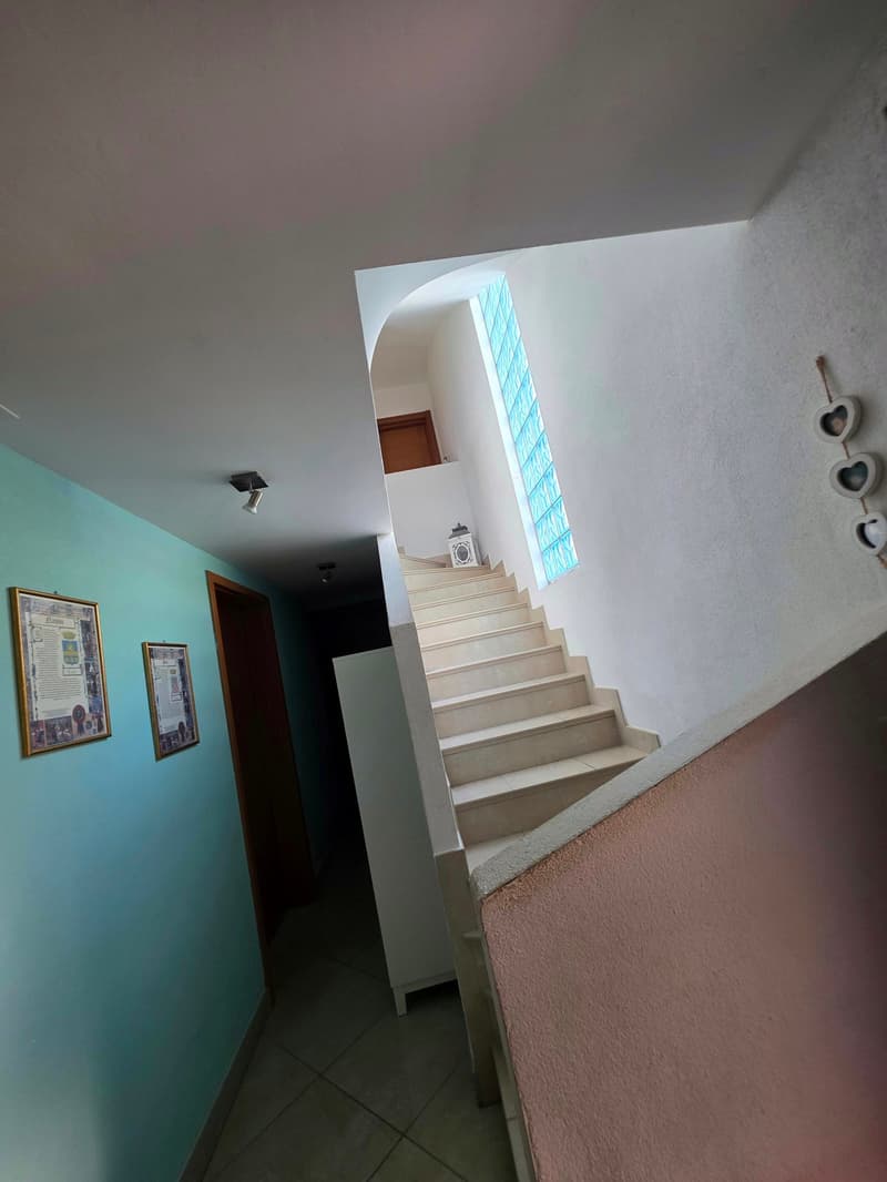 tiled floor, white walls, blue wall, framed pictures, staircase, glass window