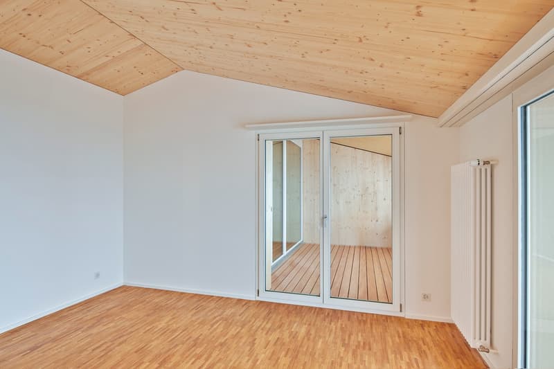 empty room with sliding doors, balcony, hardwood floor, white walls, wooden ceiling