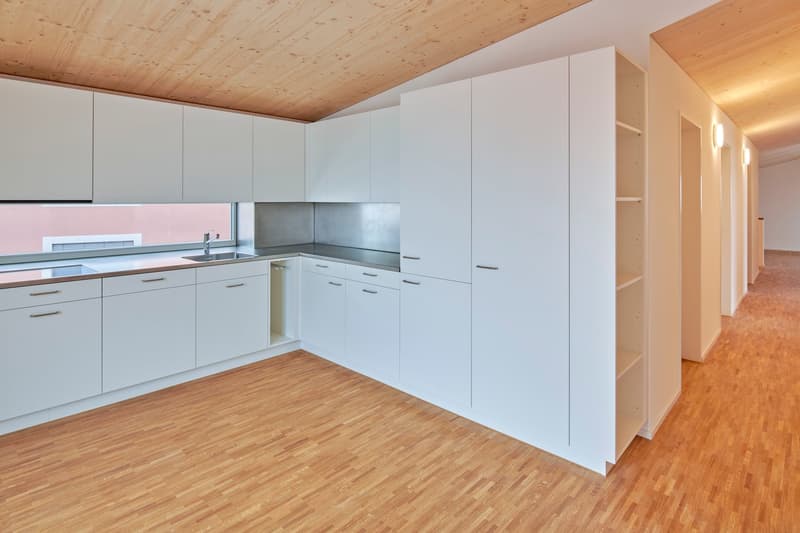 Modern kitchen with white cabinets, wooden floor, stainless steel countertop, and sink.