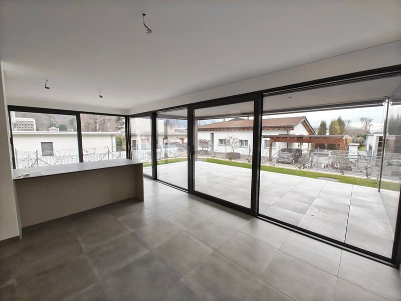Empty room with sliding glass doors, tiled floor, white walls, metal railing, exterior view