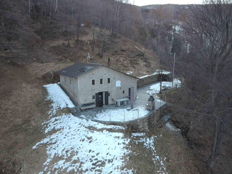Mountain house, raised ground floor, solar panels on the roof, covered porch, garden, surrounded by trees