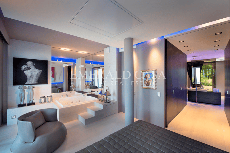Spacious master bedroom with modern decor, large windows, jacuzzi tub, fireplace, and artwork on the walls