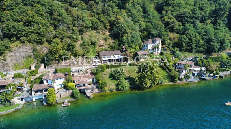 Luxury villas on the shores of a lake, surrounded by greenery, with access roads, a dock, and a pier.