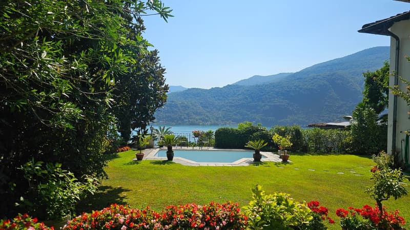 lakefront villa, pool in garden, greenery, mountains in background, patio area with garden furniture, decorative flowers