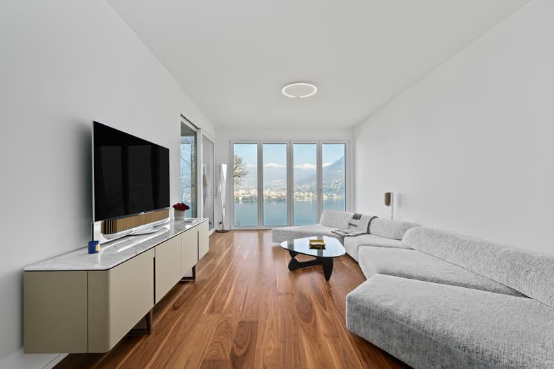 Modern living room with large windows, hardwood floor, gray sofa, coffee table, mounted television, floating entertainment center, ceiling light, scenic view