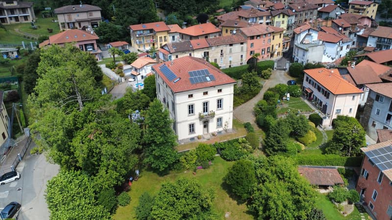 Multiple residential buildings, red roofs, solar panels, green areas, roads, cars parked