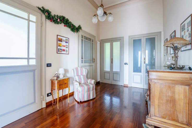wood floor, white walls, armchair, cabinet, framed pictures, chandelier, windows, door