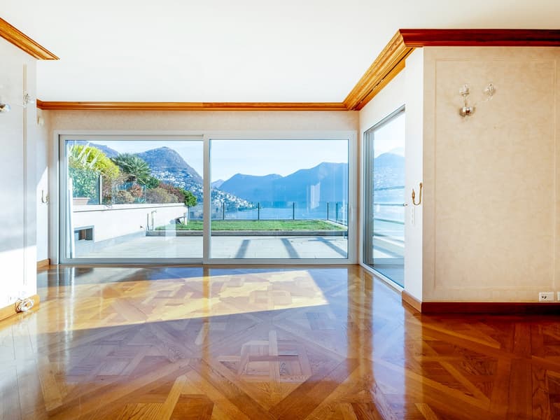 Large room with wooden floor, glass sliding doors, balcony view, large windows
