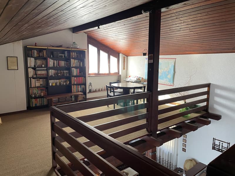 wooden ceiling, wooden floor, bookshelves, table, chairs, desk, wooden railing, map on the wall