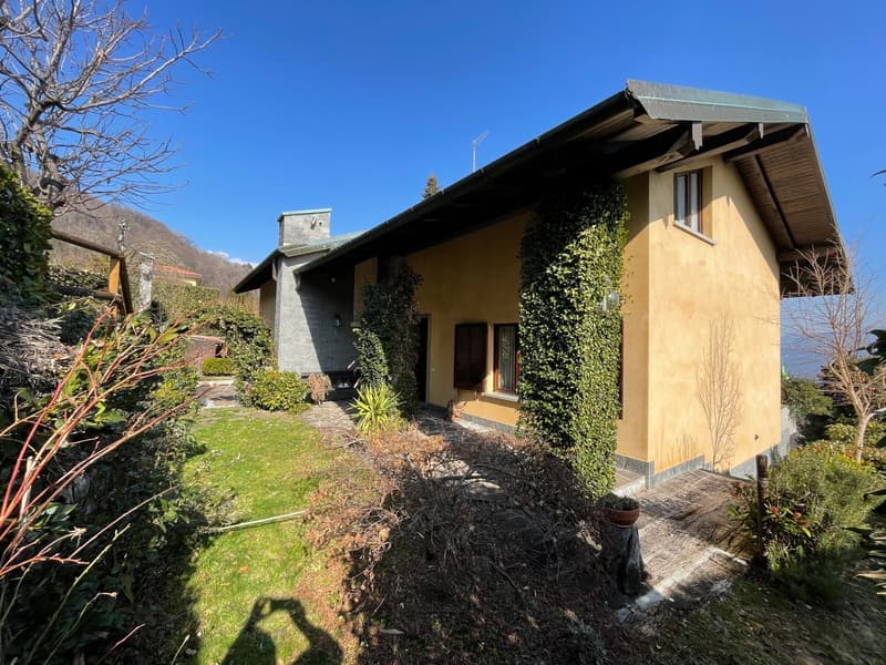 Raised ground floor house, yellow exterior, green ivy, mountain view