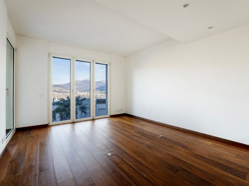 Large glass windows, hardwood flooring, white walls, no furniture