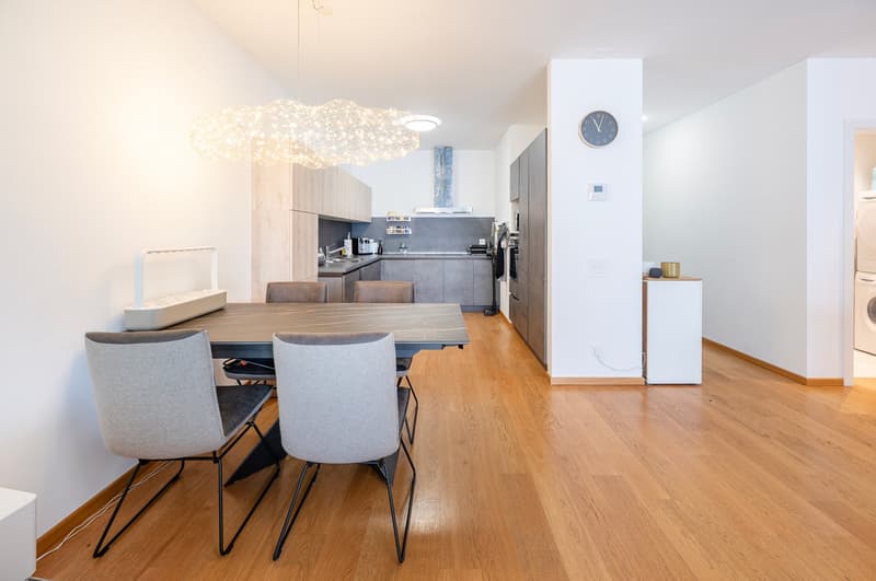 Open floor plan, wooden floor, dining table, chairs, kitchen appliances, chandelier, washing machine