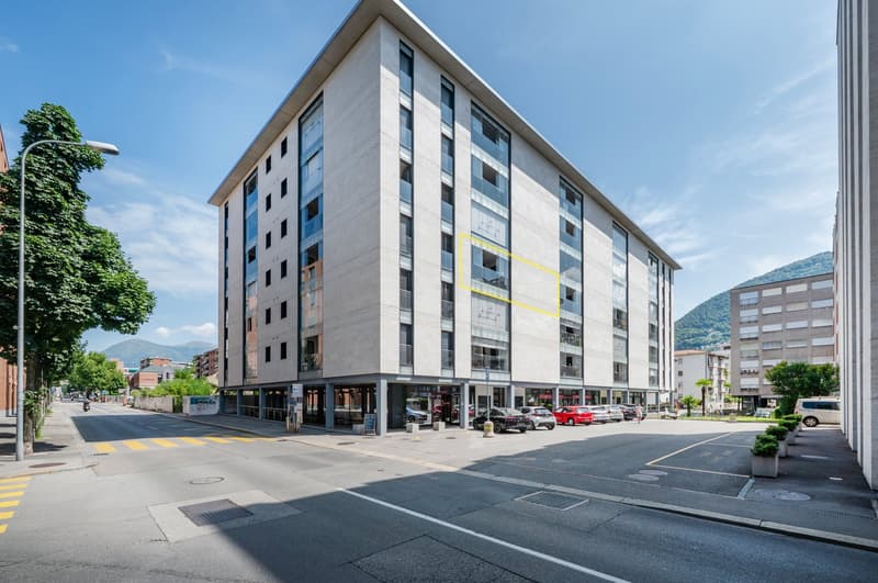 6-storey apartment building with underground parking, large windows, commercial space at the bottom, cars parked in front