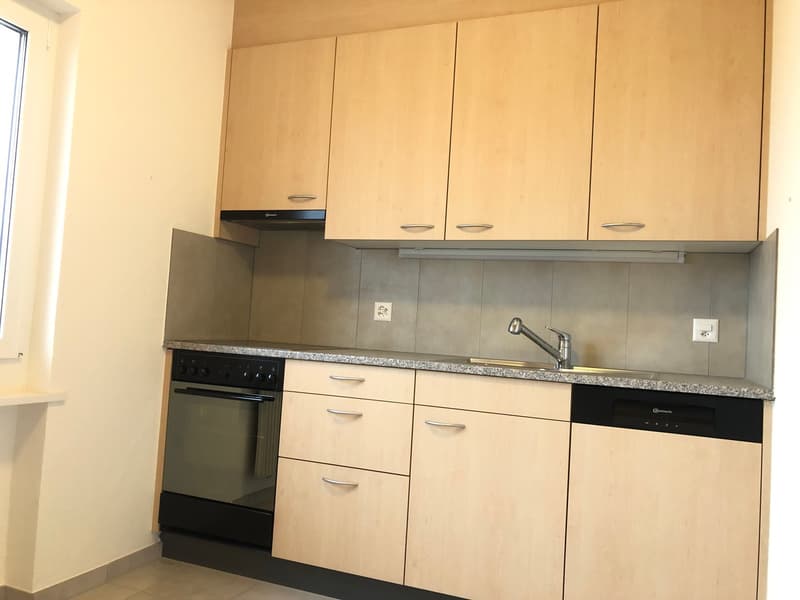 Beige cabinets, granite countertop, black oven and dishwasher, sink with faucet