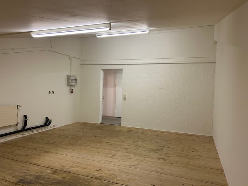 Empty room, wooden floor, white walls, mounted electrical outlet, door, pipes