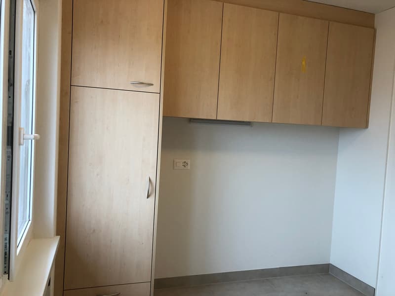 Large wooden cabinets, electrical socket, window with white frame