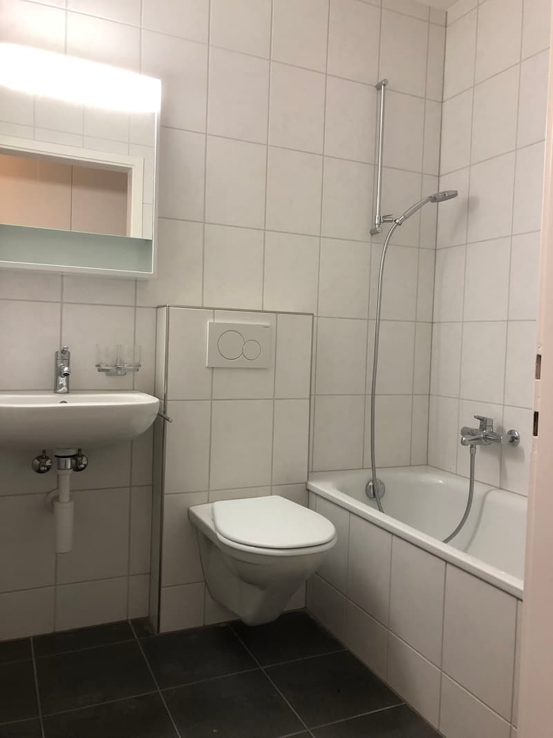 Bathroom with white tile, white toilet, white bathtub, white sink, and a mirror.