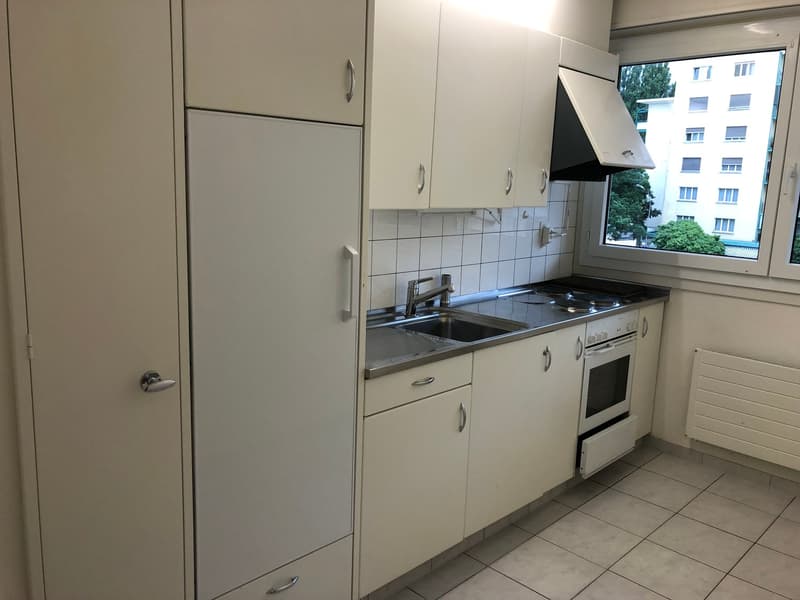 small kitchen with stove, sink, cabinets, white tile floor