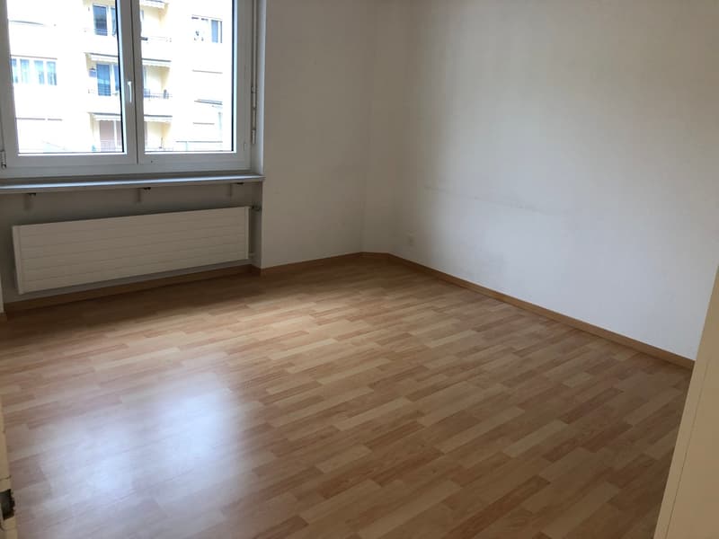 empty room with large windows, hardwood floor, white walls, a radiator
