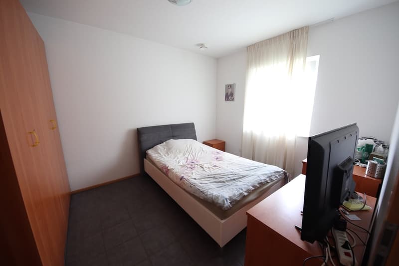 bedroom with double bed, wooden nightstand, flat screen TV, white wall, picture frame, wooden cabinet, tiled floor