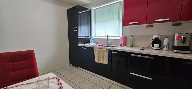 Modern kitchen with black cabinets, white countertops, tile flooring, and a dishwasher visible