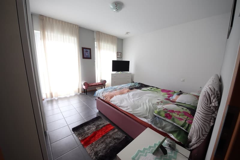 modern design, white walls, tile flooring, bed, desk, TV, window with curtains, rug