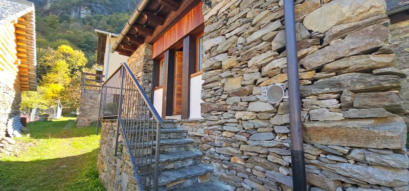 Stone wall building, wooden roof, staircase with railings, grassy area