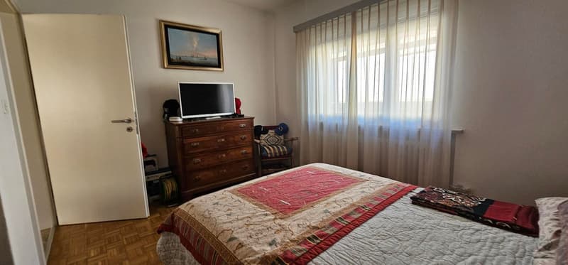 Wooden bed with textile cover, wooden furniture, TV, curtained window, wooden floor