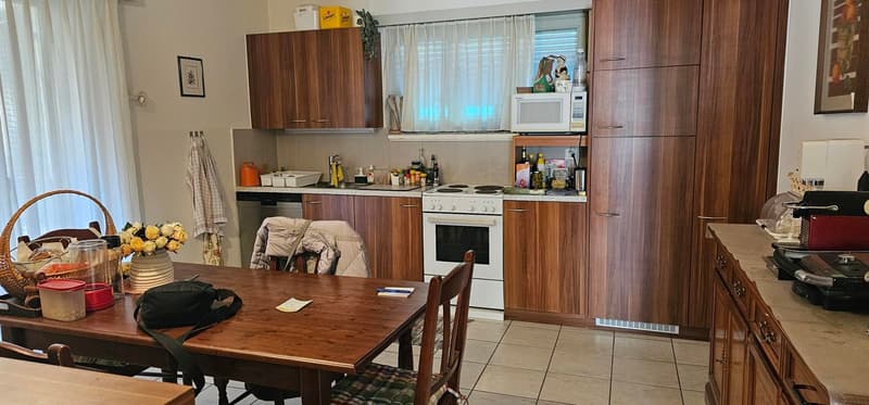 A kitchen area with a dining table, oven, microwave, wooden cabinets, and other kitchenware.
