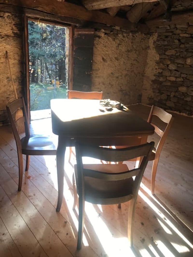 wooden floor, stone wall, wooden table, wooden chairs, open door, sunlight