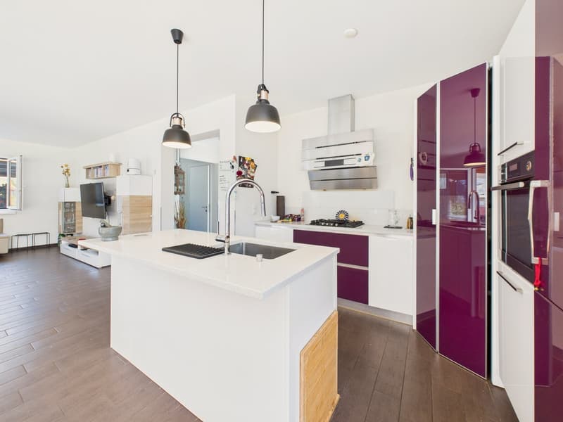 modern kitchen with white countertops, purple cabinets, island with sink, gas stove, oven, wooden floor