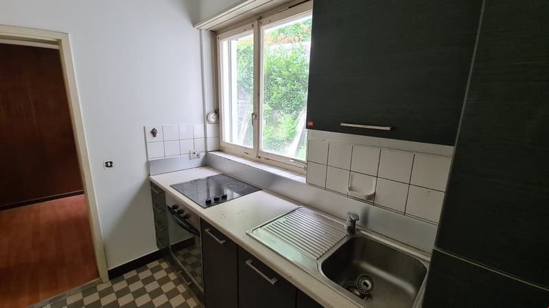 checkered floor, white walls, a gas stove, an oven, and a sink with a faucet, wooden door, white tiles, window
