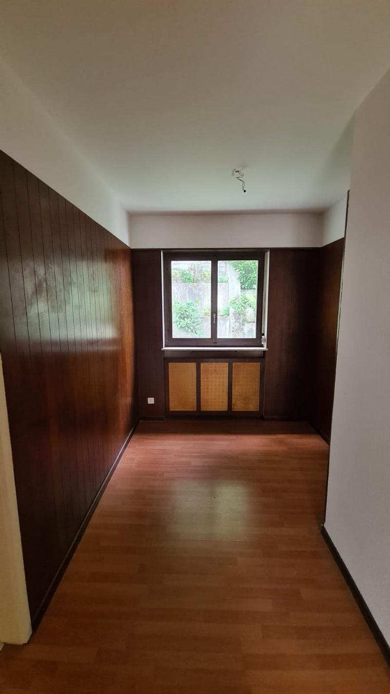 hardwood floors, brown paneling, white walls, large window, wooden radiators, exterior view