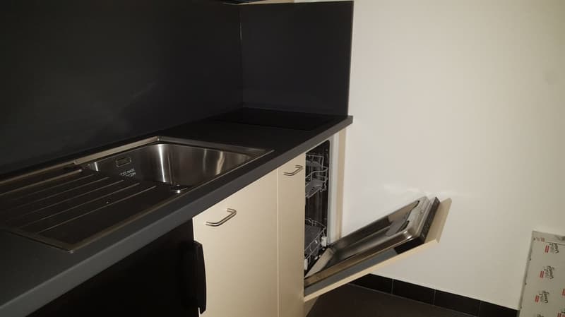 Kitchen with a sink, gas stove, dishwasher, cabinets, black countertop