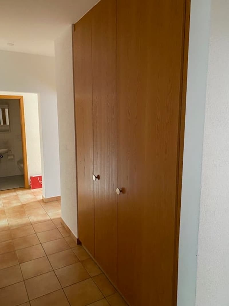 room with wooden cupboard, tile floor, door leading to a bathroom
