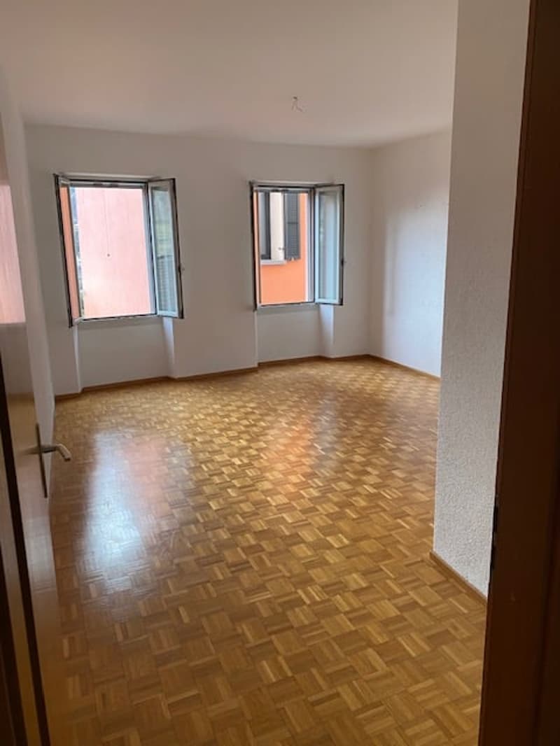empty room, wooden floor, white walls, two large windows, bright