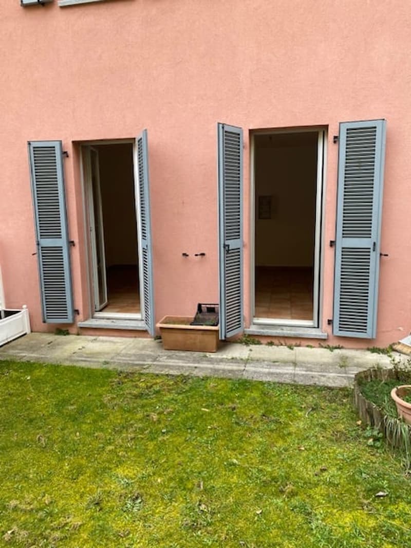 Pink house, gray shutters, open doors, small potted plants, grassy area